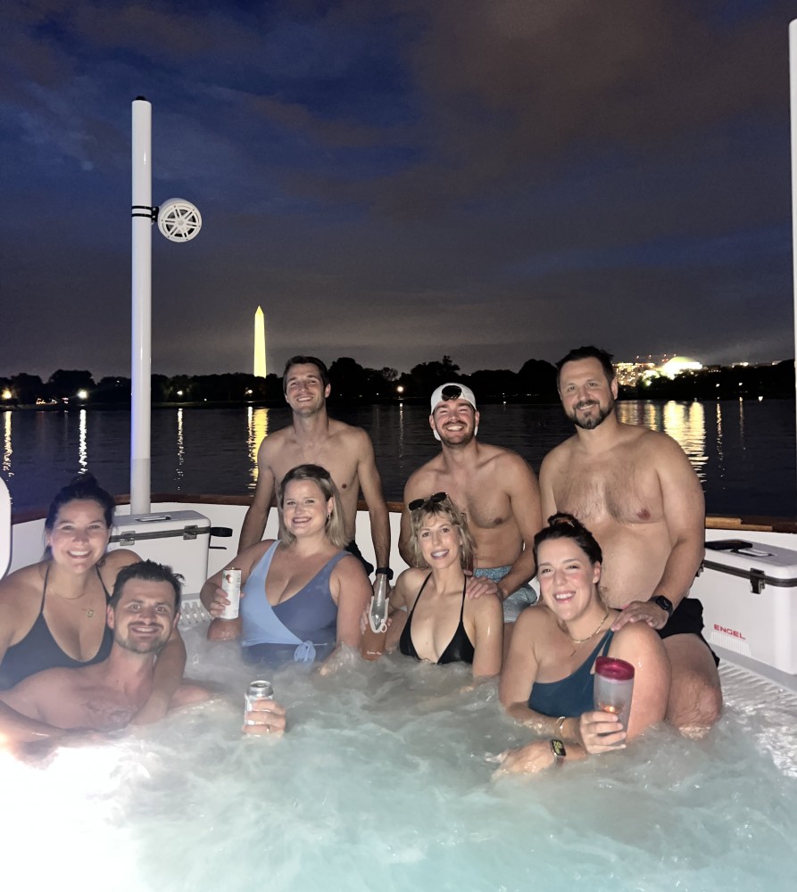 group of people in front of the washington monument soaking in the DC hot tub boat at night